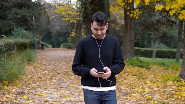 Avslappnad Ung Man Promenader Parken Lyssna Musik Slowmotion — Stockvideo