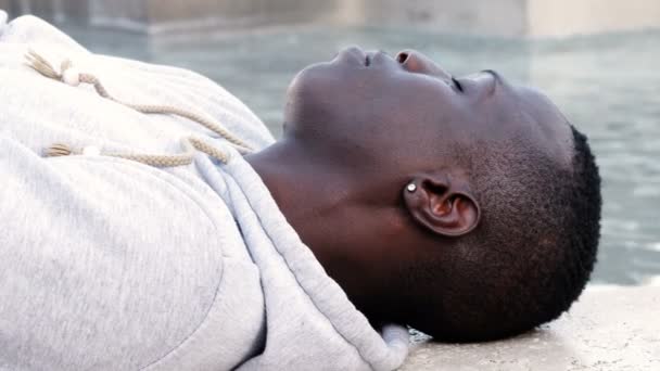 Bonito Jovem Negro Deitado Perto Rio Olhando Para Câmera — Vídeo de Stock