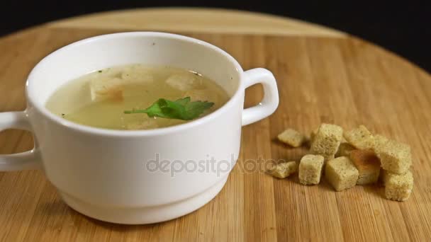 Dill falls into chicken soup with croutons. Slow motion — Stock Video