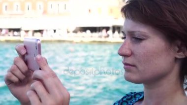 Genç kadın fotoğrafı bir deniz feneri bir Avrupa şehri kullanır smartphone içinde çeker