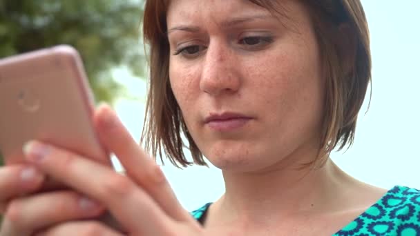 Junge hübsche Frau in Kleid mit Smartphone sitzt am Meer in der Stadt — Stockvideo