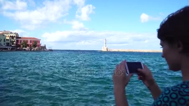 Jonge vrouw neemt de foto van een vuurtoren, in een Europese stad gebruik smartphone — Stockvideo