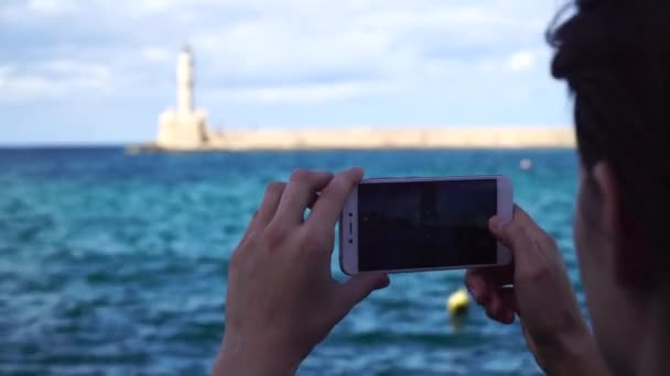Mujer joven toma la foto un faro en una ciudad europea utiliza teléfono inteligente — Vídeo de stock