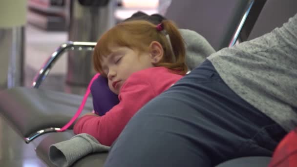 Дівчина і мами сплять в зоні очікування аеропорту. затримка рейсу — стокове відео