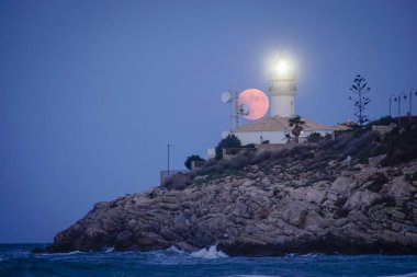 Sahildeki bir fenerin üzerinde ay tutulması