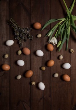 Paskalya yumurtaları ve kahverengi bir masaya çiçek