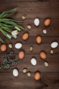 Paskalya yumurtaları ve kahverengi bir masaya çiçek