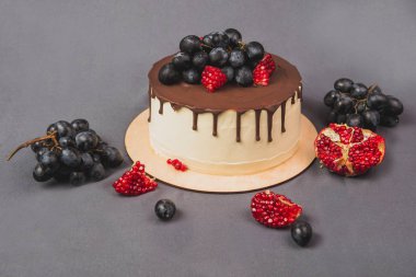 Lezzetli pasta gri bir arka plan üzerinde. Üzüm ve nar ile dekore edilmiş