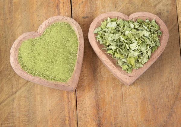 Folhas de moringa e poeira no fundo de madeira — Fotografia de Stock