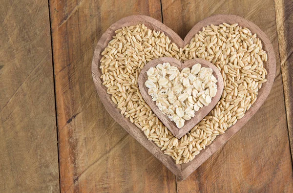 Semillas y copos de avena en forma de cuenco de madera corazón —  Fotos de Stock