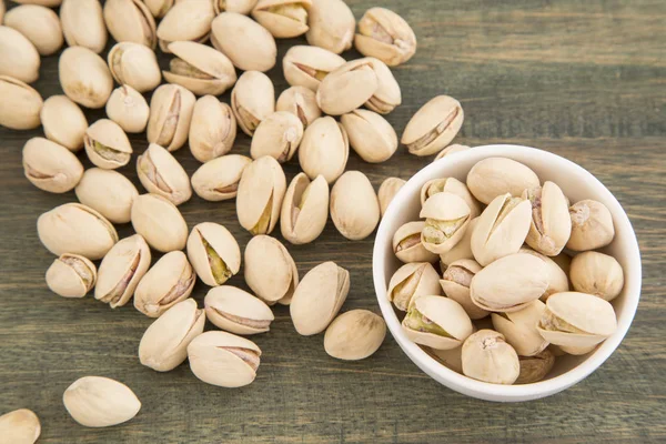 Cuenco blanco de pistachos sobre fondo de madera — Foto de Stock