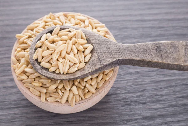 Granos de avena en cuenco de madera — Foto de Stock