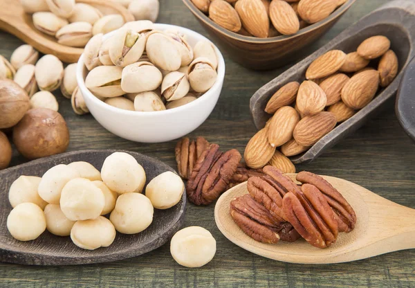 Grupo de nueces sobre mesa de madera. Almendras, pistachos, macadamia y nuez de pacana — Foto de Stock