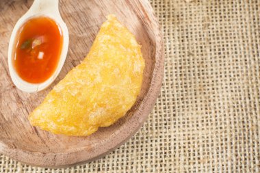 Ahşap arka planda baharatlı soslu Kolombiya böreği.