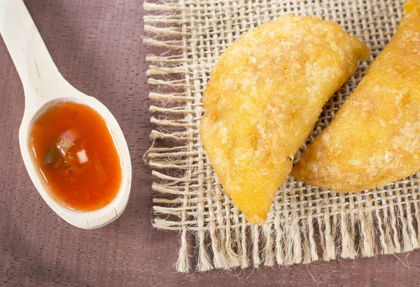 Empanada colombiana con salsa picante sobre fondo de madera —  Fotos de Stock