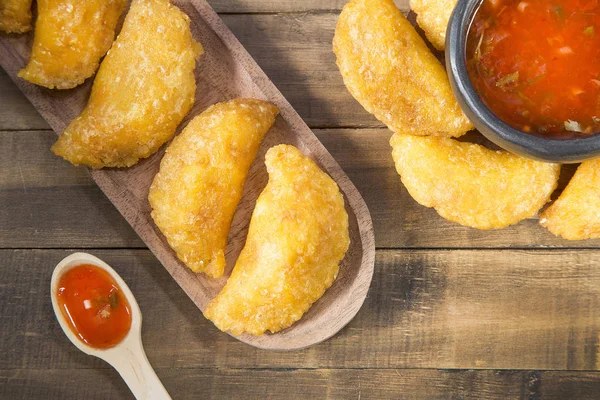 Empanada colombiana con salsa picante sobre fondo de madera —  Fotos de Stock