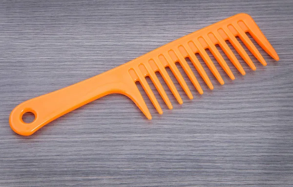 Plastic comb on wooden background