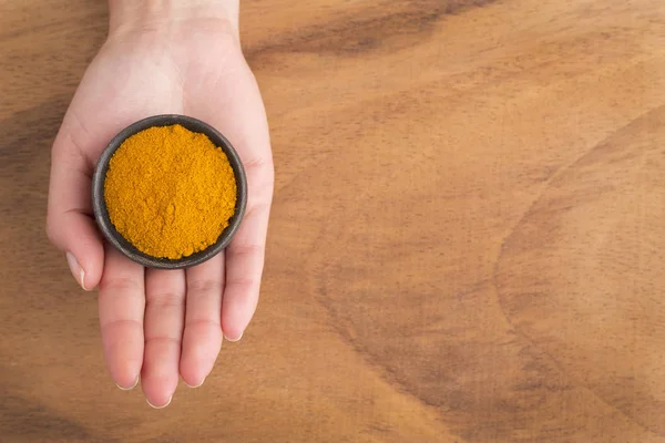 Turmeric powder in bowl between hands - Curcuma longa