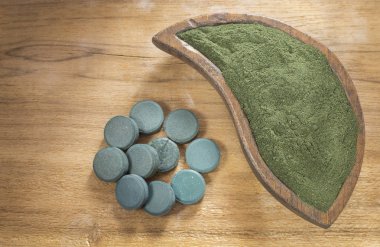 Superfood spirulina tozu ve ahşap arka plan hapları