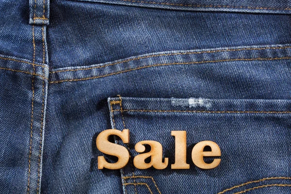 Продажа в деревянных буквах на фоне джинсов — стоковое фото