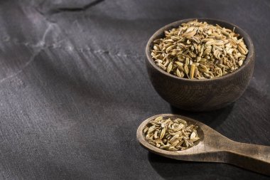 Ahşap bir kasede kurutulmuş rezene tohumları, tahta kaşıkla Foeniculum vulgare.