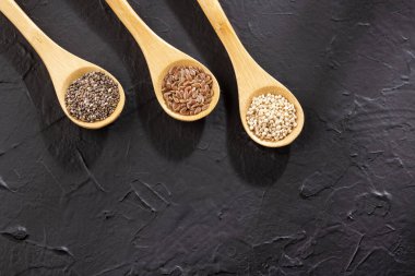 Ahşap kaşıklarda organik chia, kinoa ve keten tohumu tohumları.