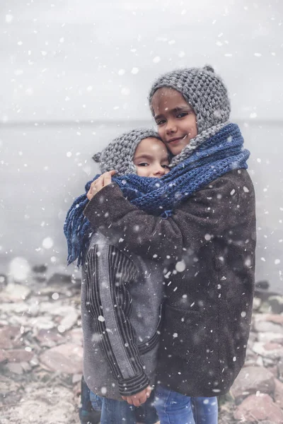 Flicka i stickad grå hatt kramar sin frusna lillebror — Stockfoto