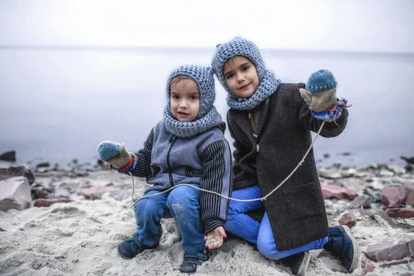 Dívka v pletený šedý klobouk sdílení rukavice se svým zmrazeným bratrem — Stock fotografie