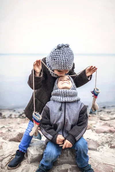Девушка в вязаной серой шляпе делится перчатками со своим замороженным братом — стоковое фото