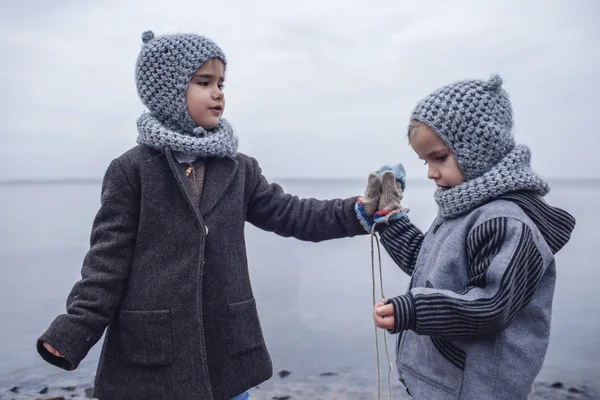 Chica de punto sombrero gris compartir guantes con su hermano congelado — Foto de Stock