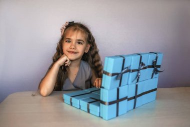 Mavi hediye kutularının yanında dizüstü bilgisayar gibi sevimli bir kız.