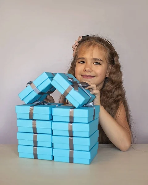 Cute girl w pobliżu niebieskich pudełek z prezentami utworzone jak dom — Zdjęcie stockowe