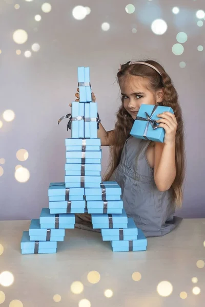 Симпатичная девушка возле голубых подарочных коробок, сформированных как Эйфелева башня — стоковое фото