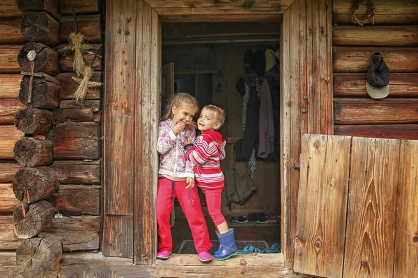 Children having rest on the doorstep of old wooden house during — Stock Photo, Image