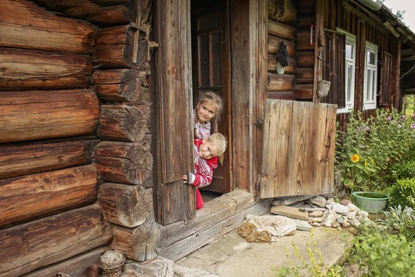Дети, отдыхающие на пороге старого деревянного дома во время — стоковое фото