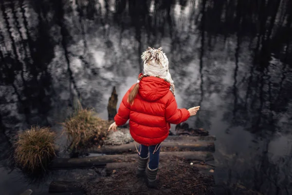 Dziewczyna w czerwonym płaszczu zatrzymuje się na brzegu jeziora sam i looki — Zdjęcie stockowe