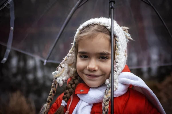 7-8 años niña en abrigo rojo con paraguas transparente caminar alo — Foto de Stock