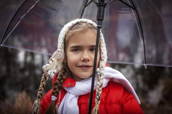 7-8 years girl in red coat with transparent umbrella walking alo — 스톡 사진