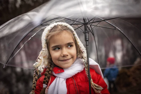 7-8 éves lány piros kabátban átlátszó esernyővel walking alo — Stock Fotó