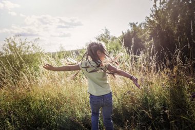 Çocuklar çayırdaki çiçeklerle yeşil çimlerde eğleniyorlar.