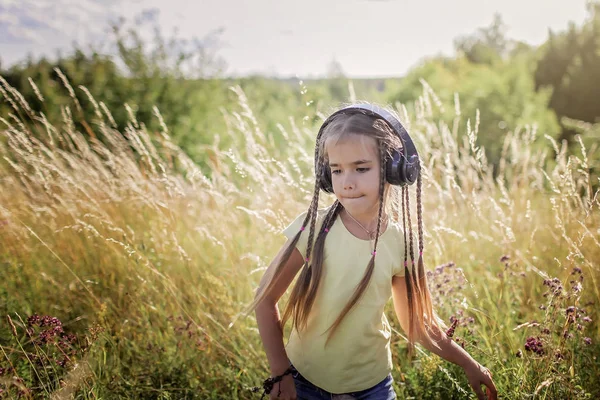 Mädchen mit vielen Zöpfen und Kopfhörern, die Musik hören und tanzen — Stockfoto