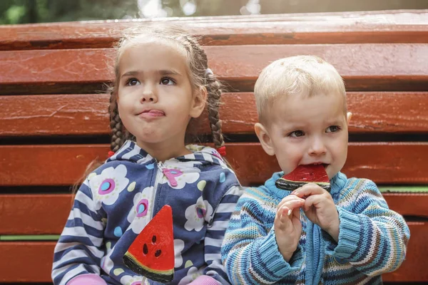 Due bambini che mangiano caramelle rosse brillanti con gusto di anguria nel — Foto Stock
