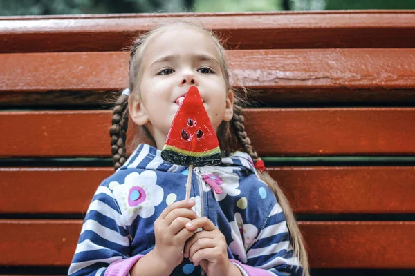 6-7 years girl eating bright red candies with watermelon taste i — Stock Photo, Image