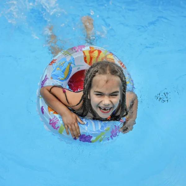 행복하고 귀여운 소녀는 휴식을 부풀어 오르는 울긋불긋 소리로 물에서 수영장에서 — 스톡 사진