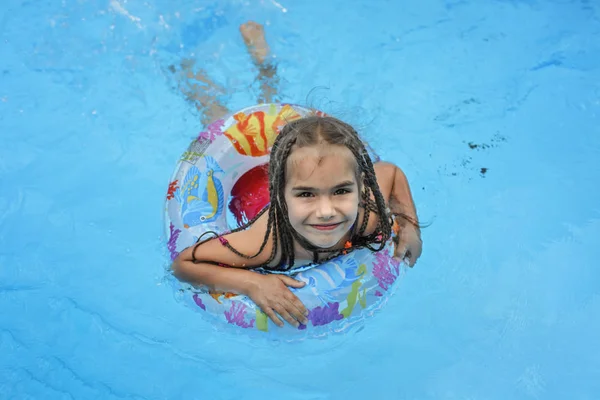 행복하고 귀여운 소녀는 휴식을 부풀어 오르는 울긋불긋 소리로 물에서 수영장에서 — 스톡 사진