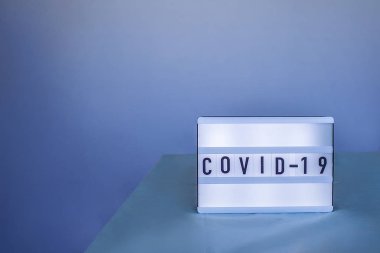 Mavi arka plan, sağlık ve tıp konseptine hızla yayılan Coronavirus 'la ilgili dikkat çekmeden önce solunum maskesi ve ilaç eldivenleri takan bir doktor.