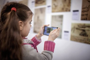 Büyütülmüş gerçeklik mobil uygulaması ile çağdaş bir sanat sergisini araştıran meraklı kız, günlük hayatta gelecek teknolojisi, kapalı bir yaşam tarzı.