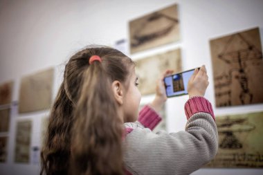 Büyütülmüş gerçeklik mobil uygulaması ile çağdaş bir sanat sergisini araştıran meraklı kız, günlük hayatta gelecek teknolojisi, kapalı bir yaşam tarzı.