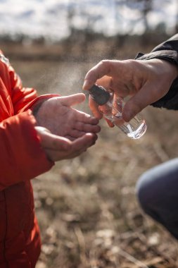 Maskeli baba ve kızı ellerinde alkol spreyi ya da bakteri spreyi ile karantina zamanındaki mikrop, bakteri ve virüsün yayılmasını önlüyor.