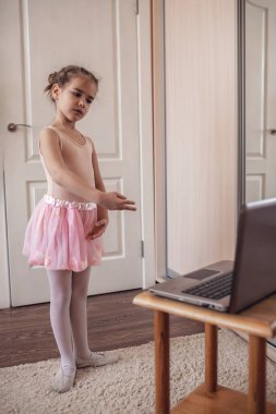 Pretty young ballerina practicing classic choreography during online class in ballet school, social distance during quarantine, self-isolation, online education concept clipart